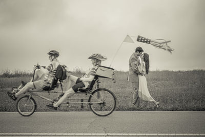 People riding bicycle on road against sky