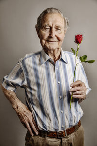 Portrait of smiling senior man with red rose