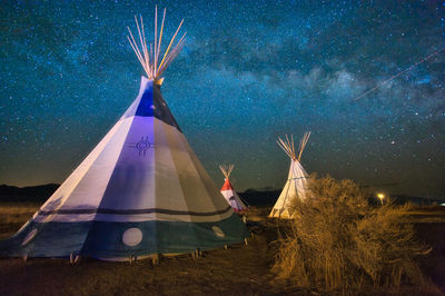 Digital composite image of tent on field against sky at night