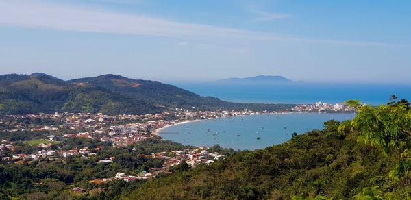 Scenic view of sea by townscape against sky