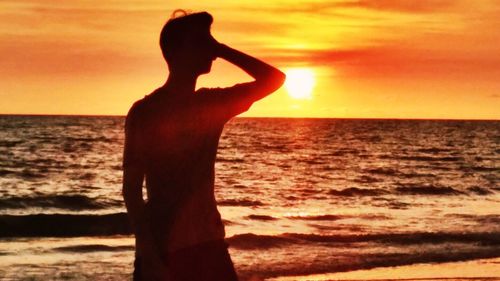 Silhouette man standing on beach during sunset