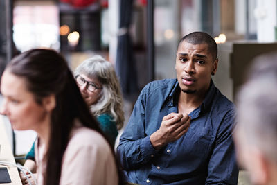 Businessman gesturing while discussing with colleagues in meeting at creative office