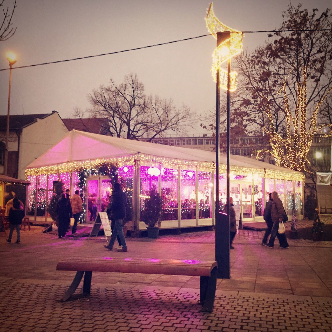 building exterior, architecture, large group of people, built structure, person, men, city, street, street light, illuminated, city life, lighting equipment, tree, lifestyles, walking, leisure activity, sky, mixed age range, outdoors