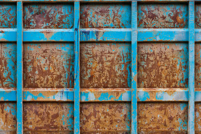 Rusted reinforced container wall with leftovers of blue paint, flat full-frame background and