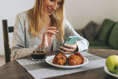 Midsection of woman using mobile phone while sitting on table