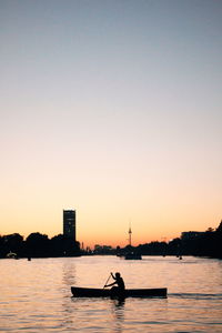 Silhouette man on boat in river against clear sky