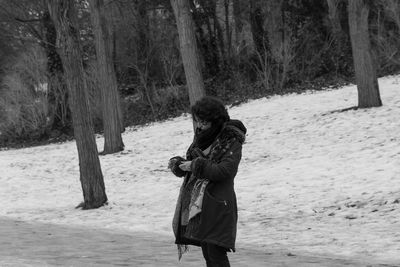 Woman standing by tree trunk in forest