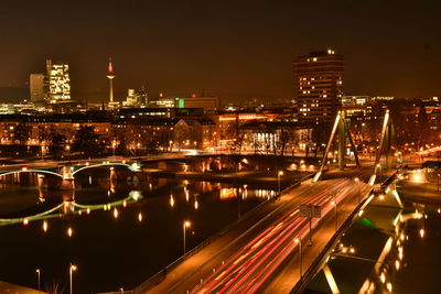 High angle view of illuminated city by river against sky at night
