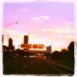 Road in city against sky at sunset