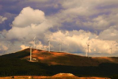 Wind turbines on field against sky