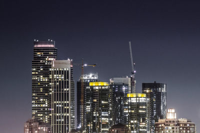 Illuminated cityscape against clear sky at night