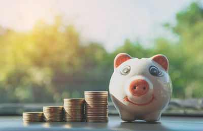 Stacked coins and piggy bank on table