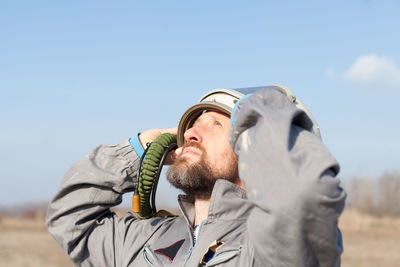 Close-up of man looking up against sky