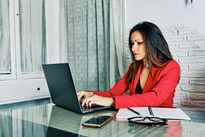 Young woman using mobile phone while sitting on table