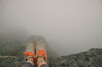 Low section of person on rock during foggy weather