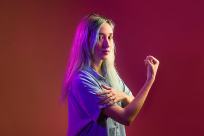 Portrait of young woman with arms crossed standing against black background