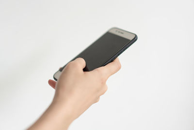 Close-up of hand holding smart phone over white background