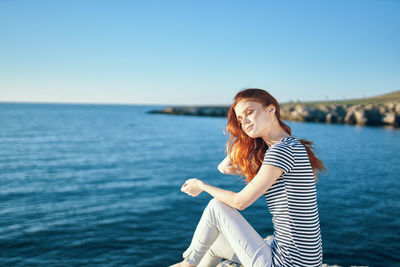 Young woman against sea against clear sky