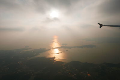 Silhouette airplane flying over landscape against sky during sunset