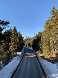 Road amidst trees against clear sky during winter