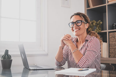 Portrait of smiling woman sitting on table at home