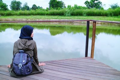 Rear view of girl sitting by lake