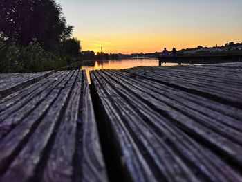 Surface level of wooden posts on beach against sky during sunset