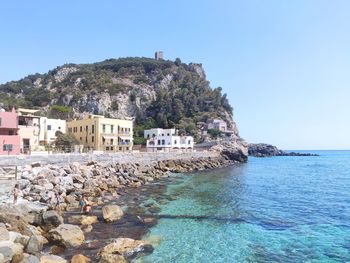 Scenic view of sea by buildings against clear sky