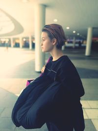 Side view of young woman standing against wall