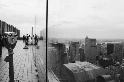 People standing by modern buildings in city against sky