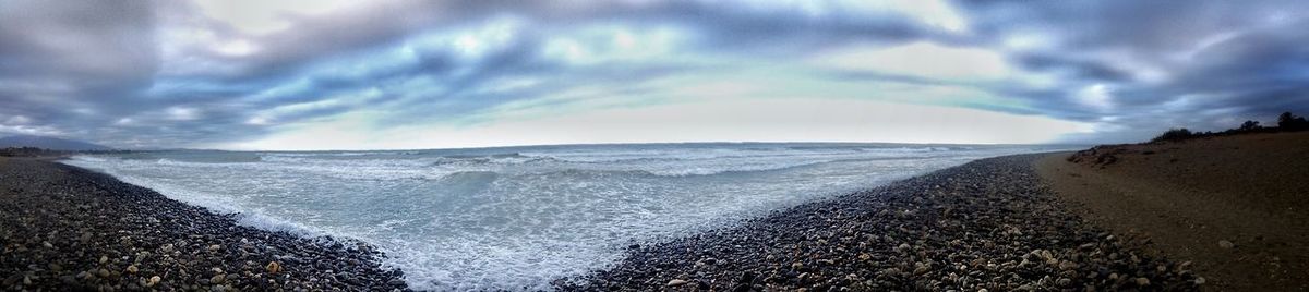 Scenic view of beach against cloudy sky