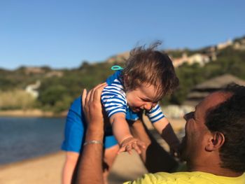 Close-up of happy father holding cute baby boy at beach