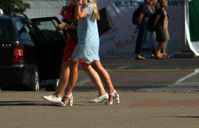 Low section of women standing on road