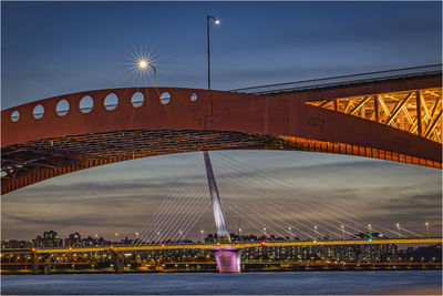 Illuminated bridge against sky at night