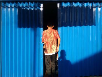 Rear view of man standing against blue sky