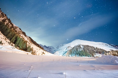 Scenic view of snow covered mountains against sky at night