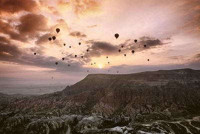 Hot air balloons flying over rocks against sky