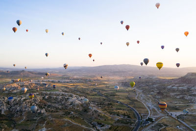 Hot air balloons flying over landscape against sky