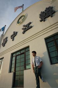 Low angle view of teenage boy standing by school building