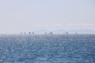 Scenic view of ocean and sailing  boats against sky