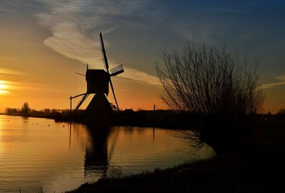 Silhouette of traditional windmill against sky during sunset