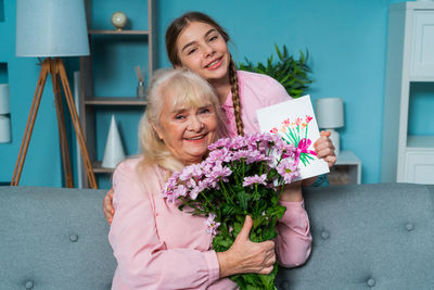 Portrait of grandmother and granddaughter holding flower at home