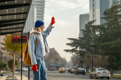 Rear view of woman with arms outstretched standing on street