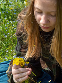 Teenager caucasian girl picking up flowers in springtime in a garden outdoors a sunny day