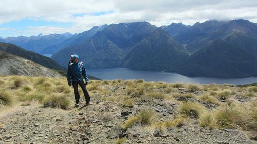 Man standing at lakeshore against mountains