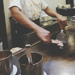 Midsection of man preparing food in commercial kitchen