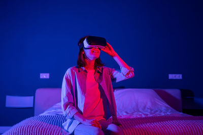 Young woman using mobile phone while sitting on bed at home