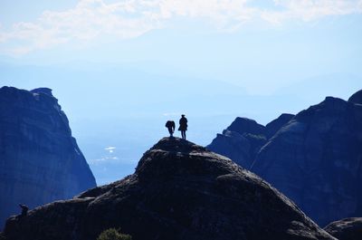 Low angle view of silhouette man standing on cliff against sky