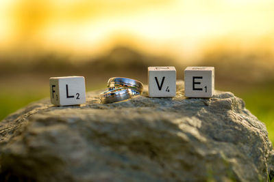 Close-up of love blocks with wedding rings on rock