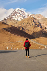 Back view of traveler with backpack hiking alone in mountainous region